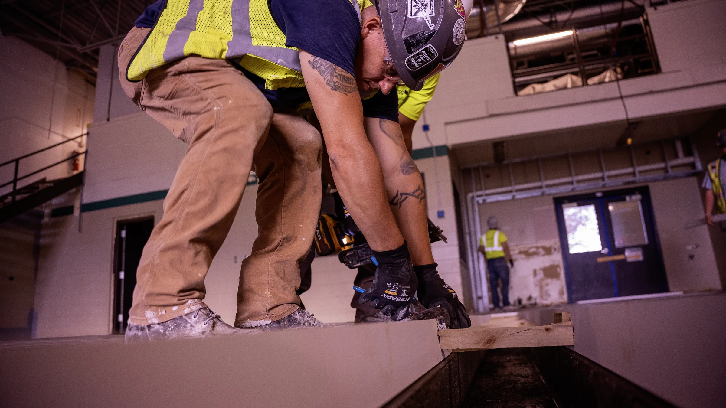 Two crew members assembling a wood pour-stop form along a construction line